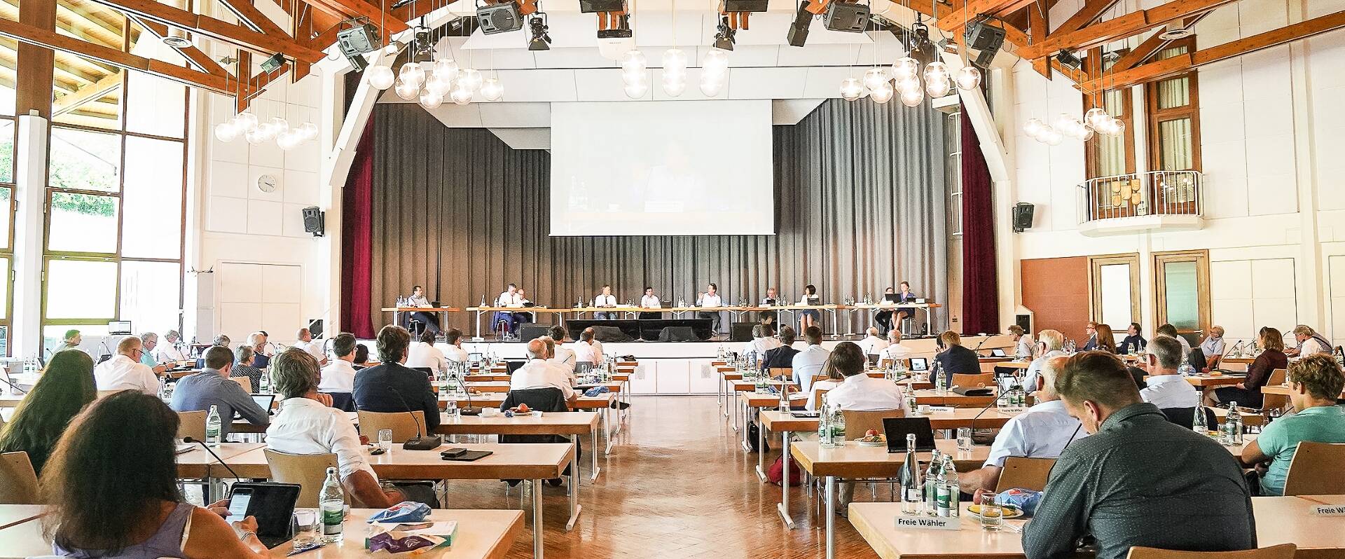 Blick in einen großen Sitzungssaal mit einer Bühne und vielen Rednern